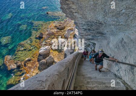 I visitatori salgono le scale a Escalier du roi d'Aragon in roccia calcarea sullo stretto di Bonifacio a Bonifacio, Corse-du-Sud, Corsica, Francia Foto Stock