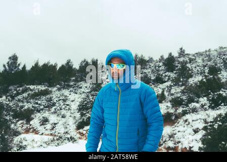 Hiker cammina giù per la montagna durante una neve coperta da un cappotto. Foto Stock