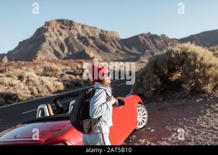 Donna in piedi sulla strada vicino alla auto convertibile, viaggiando sulla valle del dessert Foto Stock