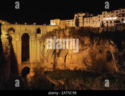 Foto aerea drone punto di vista enorme gola e architettura antica, città luci di strada notte vista di Ronda in provincia spagnola di Málaga. Spagna Foto Stock