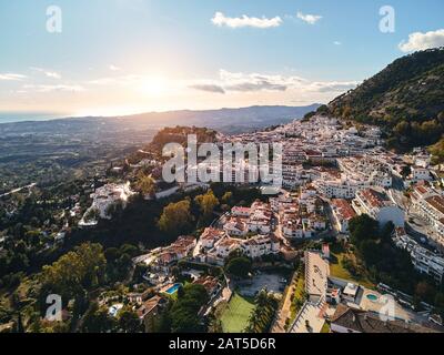 Foto aerea Vista distante incantevole Mijas pueblo, tipico villaggio andaluso di montagna dipinto di bianco, case sui tetti, piccola città, Malaga, Spagna Foto Stock