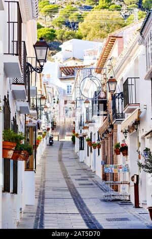 Villaggio collinare di Mijas, strada vuota che conduce in su, case residenziali dipinte di bianco con le piante appese sulle pareti, Málaga, Costa del Sol, Spagna Foto Stock