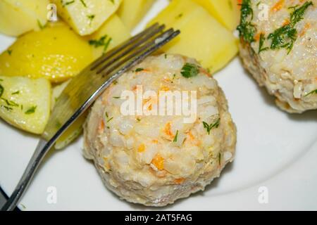 polpette di carne con patate bollite e carote bollite su un piatto bianco con una forchetta. Primo piano Foto Stock