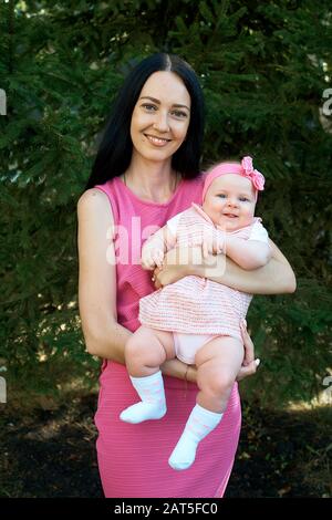 Una giovane madre tiene la sua figliuola nelle sue braccia Foto Stock