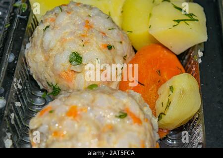 polpette di carne con patate bollite e carote bollite in un contenitore di plastica su sfondo scuro. Primo piano Foto Stock