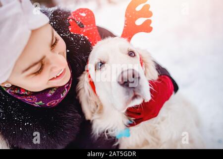 Felice giovane donna abbraccia cane Golden Retriever in inverno giorno. Concetto di amicizia Foto Stock