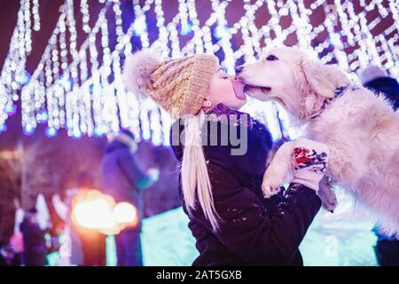 Devozione del cane, Labrador Retriever leccano bacio mistress in inverno nel parco, in illuminazione di sfondo. Amicizia e amore concetto animale Foto Stock