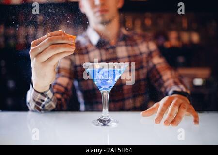 Grande cocktail in Martini glass con gocce di spray è preparato da barman Foto Stock