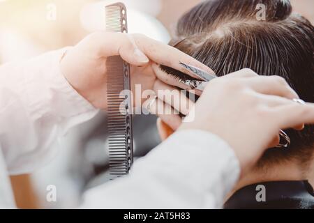 Barbiere master parrucchiere fa acconciatura e stile con forbici e pettine, concetto Barbershop per gli uomini Foto Stock