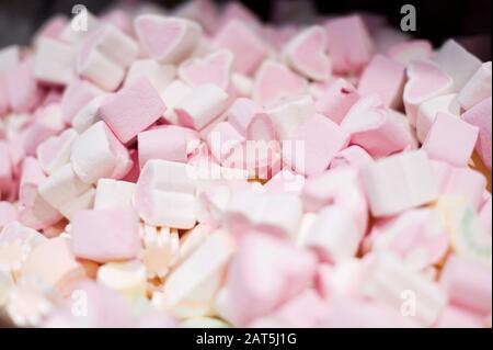 una manciata di dolci marshmallows a forma di cuore, uno di loro è a fuoco Foto Stock