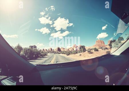 Guida al sole, immagine vintage tonata di una strada presa dal sedile anteriore di un'auto, lente flare presente, USA. Foto Stock