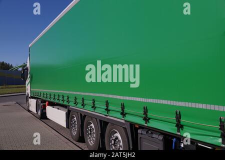 Trasporto di veicoli. Vista del telone verde che copre il semirimorchio del veicolo. Foto Stock