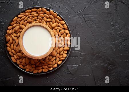 Composizione di semi di mandorle e latte, posto su fondo di pietra nera. Foto Stock