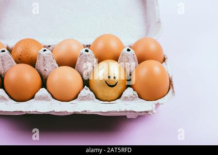 Faccia sorridente. Uova di pollo crude in una scatola di uova aperta. Cibo sano naturale e agricoltura biologica. Foto Stock