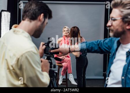 focus selettivo di makeup artista applicare cosmetici decorativi sul modello in studio fotografico Foto Stock