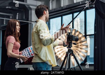 attraente art director che tiene collage foto e guarda il fotografo Foto Stock