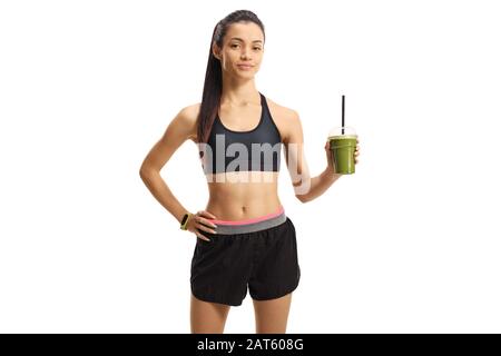 Giovane donna in abbigliamento sportivo che tiene una sana scossa verde in una tazza isolata su uno sfondo blu Foto Stock