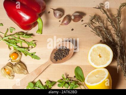 spezie e verdure su una tavola di legno con un letto al centro della cornice Foto Stock