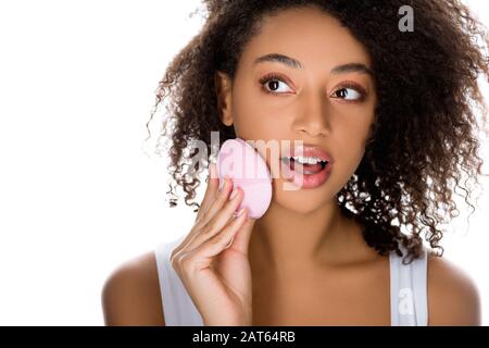 ragazza afroamericana shockata usando spazzola facciale di pulizia del silicone, isolata su bianco Foto Stock