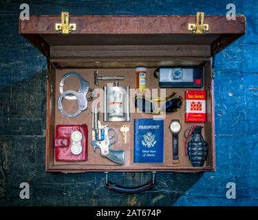 Una vista dall'alto di una valigetta in pelle di vecchio stile con oggetti da viaggio pericolosi accuratamente disposti all'interno in modo ordinato Foto Stock