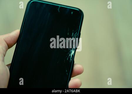 Schermo rotto dello smartphone in mano / telefono cellulare schermo rotto attendere cambiare schermo film nel concetto di officina di riparazione Foto Stock