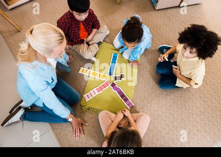 Vista aerea dell'insegnante che gioca con i bambini gioco educativo sul pavimento in classe montessori Foto Stock