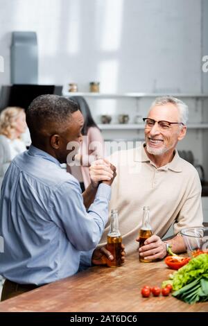 l'uomo afroamericano tiene le mani e parla con un amico sorridente in cucina