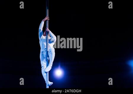 bilanciamento acrobat mentre tiene palo metallico in arena di circo Foto Stock