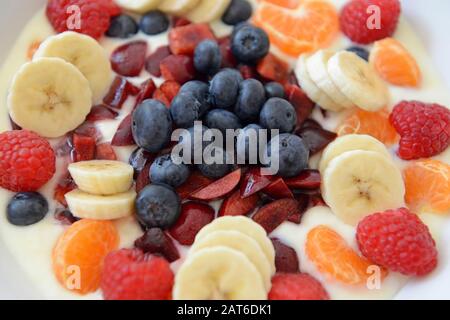 Una bella ciotola di frutta fresca mista e yogurt sul tavolo da pranzo in una casa in Sussex Foto Stock