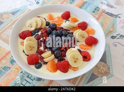 Una bella ciotola di frutta fresca mista e yogurt sul tavolo da pranzo in una casa in Sussex Foto Stock