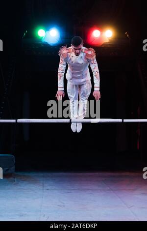 bella ginnastica in costume in equilibrio vicino alla pole in arena di circo Foto Stock