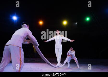 fuoco selettivo di aria bello acrobat bilanciamento su palo vicino agli uomini in circo Foto Stock