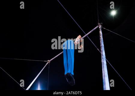 vista ad angolo basso della ginnastica flessibile che si esibisce su barre orizzontali nell'arena del circo Foto Stock