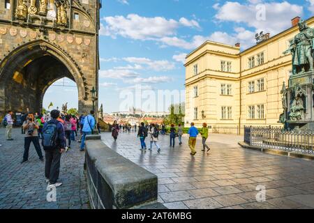 I turisti passano dalla statua di Carlo IV e dal Museo del Ponte attraverso la torre della Città Vecchia con la Cattedrale di San Vito in vista a Praga, in Cechia. Foto Stock