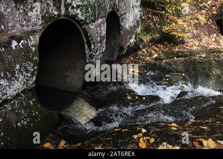 L'acqua scorre attraverso i culverts sotto un ponte di pietra lichen-coperto. NelL'Autunno 2018, Nell'Area Naturale Statale Di Houghton Falls, Bayfield Co. Wisconsin. Foto Stock