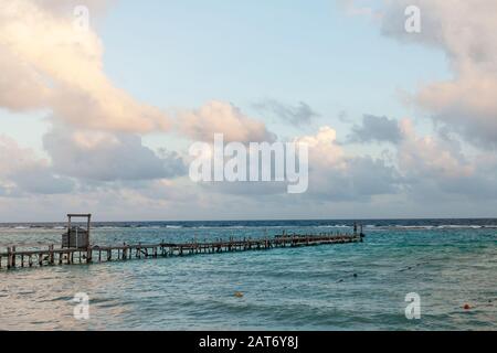 Un molo di legno ramgrillo si estende sull'acqua del Mar dei Caraibi a Mahahual, o Majajual, Quintana Roo, Messico. Foto Stock