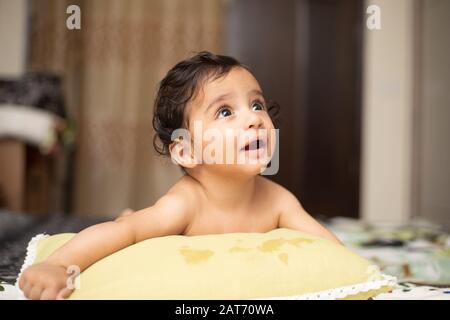 Ritratto di Sei mesi bambino indiano infantile Con sorridente e giocare con la famiglia in camera da letto con illuminazione naturale Foto Stock