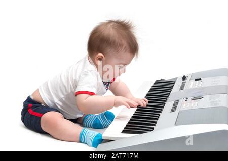 Piccolo bambino che suona su piano (sintetizzatore), isolato su bianco Foto Stock