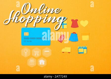 flat lay con carta di credito blu modello vicino a icone di shopping isolato su arancione con online shopping illustrazione Foto Stock