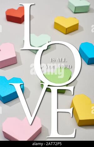 Cuori decorativi multicolore su sfondo grigio con amore è tutto ciò che serve illustrazione Foto Stock