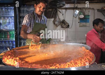 Un cuoco ad una stalla di cibo a Mumbai, India, fa 'bhaji', una mescolanza di verdure e parte del cibo indiano poco costoso e popolare o dell'alimento di strada Pad Bhaji Foto Stock