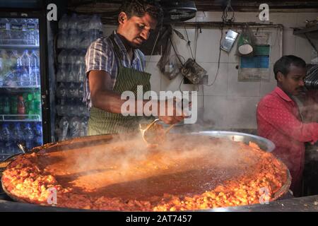 Un cuoco ad una stalla di cibo a Mumbai, India, fa 'bhaji', una mescolanza di verdure e parte del cibo indiano poco costoso e popolare o dell'alimento di strada Pad Bhaji Foto Stock