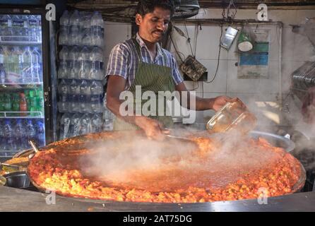 Un cuoco ad una stalla di cibo a Mumbai, India, fa 'bhaji', una mescolanza di verdure e parte del cibo indiano poco costoso e popolare o dell'alimento di strada Pad Bhaji Foto Stock