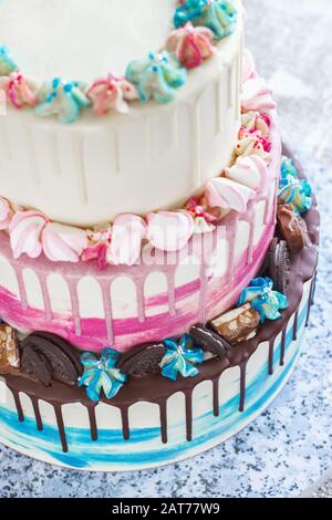 Torta colorata a tre livelli con macchie colorate di cioccolato su sfondo chiaro. Foto per un menu o un catalogo dolciario, la torta nuziale Foto Stock