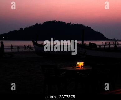 Romantica cena a lume di candela su un bel cielo rosa serale su una spiaggia accogliente Foto Stock