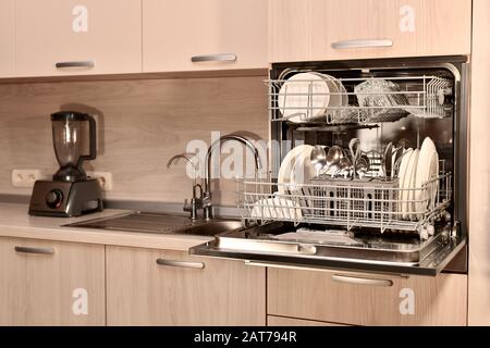 Frammento della cuffia da cucina con lavastoviglie aperta, convenientemente installata a livello della cintura dell'amante. Foto Stock