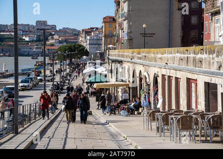 Porto, Portogallo - 20 gennaio 2020: Folle di turisti camminano lungo il quartiere Ribeira, la zona storica di Porto che si affaccia sul fiume Douro e Vila N. Foto Stock