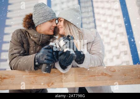 Amorevole coppia bevande calde tè o caffè da tazze thermos sulla strada invernale in pista di ghiaccio Foto Stock