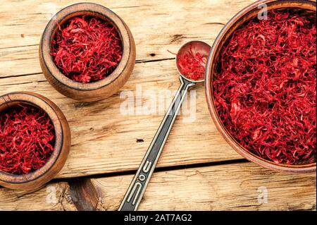 Spezia di zafferano rosso organico grezzo su sfondo di legno Foto Stock