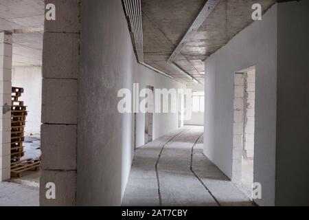 Lungo corridoio luminoso in un nuovo edificio. Appartamenti completati senza riparazione da parte del costruttore. Fase finale costruzione casa di schiuma blocco bianco Foto Stock